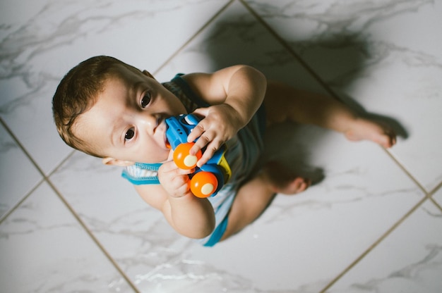 Hooghoekbeeld van baby jongen met speelgoed op de vloer thuis