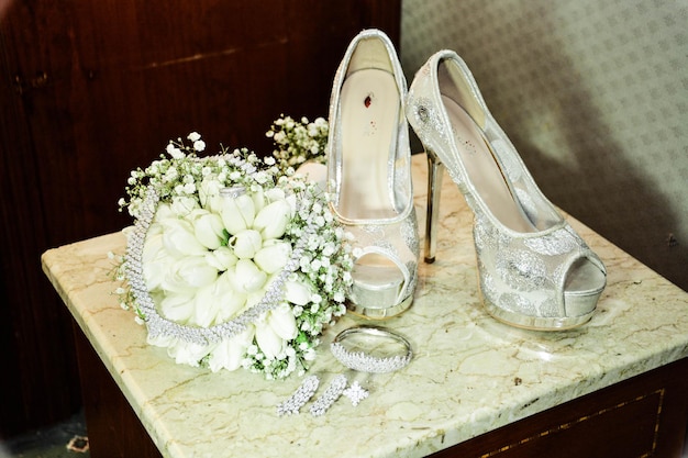 Hooghoekbeeld van bloemen met sieraden en sandalen op tafel