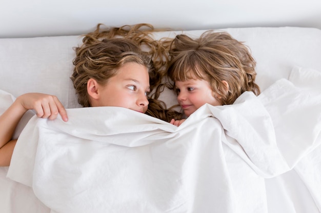 Hooghoekbeeld van broers en zussen die op bed liggen