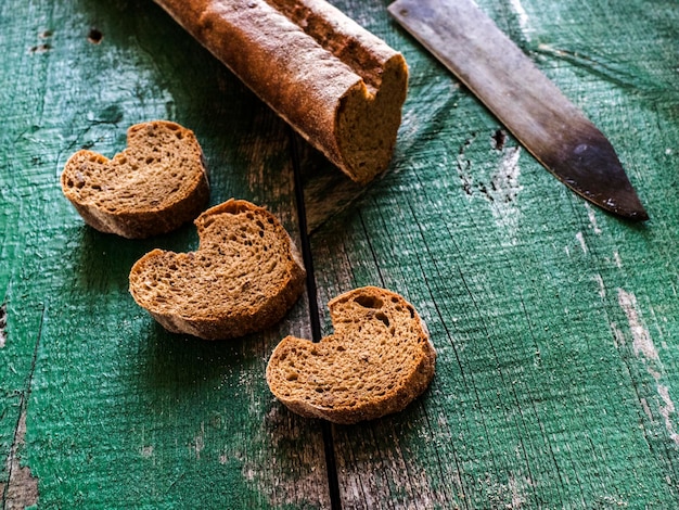 Hooghoekbeeld van broodbrood en mes op oude groene tafel