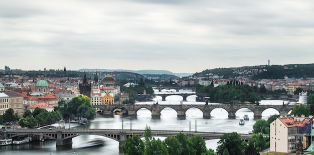 Hooghoekbeeld van bruggen over de rivier de Vltava tegen een bewolkte hemel