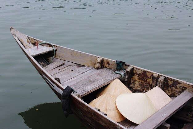 Hooghoekbeeld van conische hoeden in Aziatische stijl in een boot die aan de rivier is aangemeerd