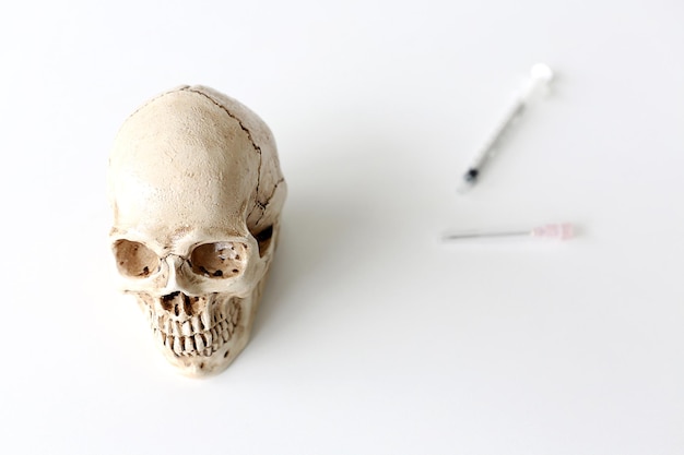 Hooghoekbeeld van de menselijke schedel door een spuit op een witte achtergrond