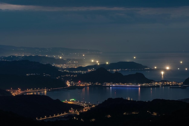 Hooghoekbeeld van de verlichte stad vanaf de zee tegen de lucht