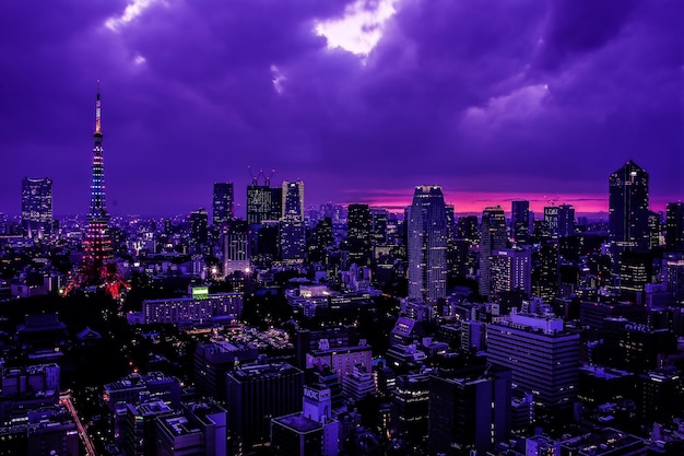 Hooghoekbeeld van de verlichte toren van Tokio door stadsbeeld tegen bewolkte hemel in de schemering
