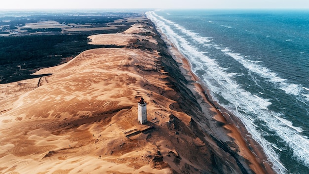 Hooghoekbeeld van de vuurtoren op de heuvel bij de zee