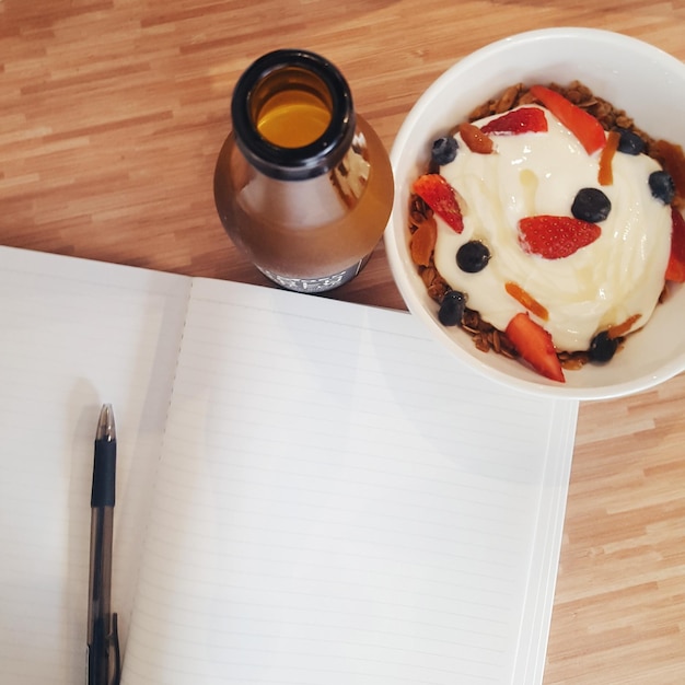 Foto hooghoekbeeld van dessert en drankje met een leeg boek op tafel.