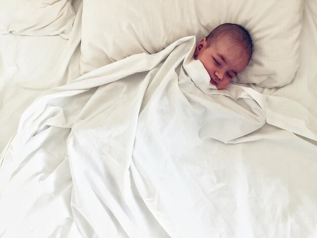 Foto hooghoekbeeld van een baby die thuis op het bed slaapt