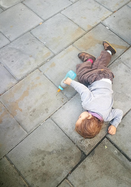 Hooghoekbeeld van een baby jongen met een fles op het voetpad