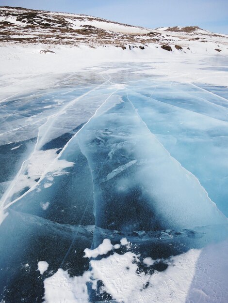 Hooghoekbeeld van een bevroren meer tegenover een met sneeuw bedekte berg