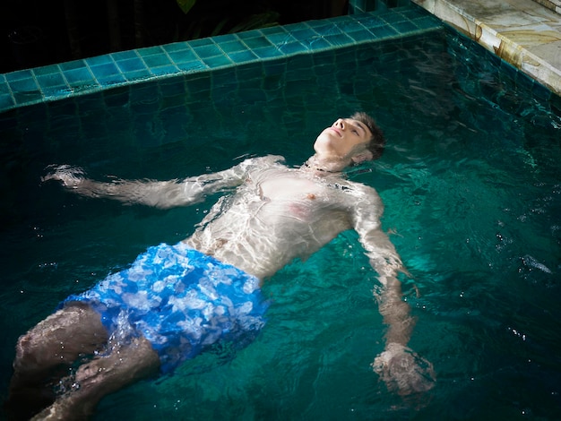 Hooghoekbeeld van een jonge man zonder hemd die in het zwembad zwemt