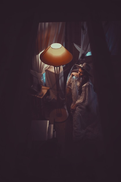 Hooghoekbeeld van een jonge vrouw door een verlichte vloerlamp