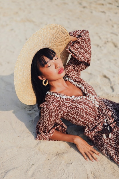 Foto hooghoekbeeld van een jonge vrouw met een hoed die op het strand zit