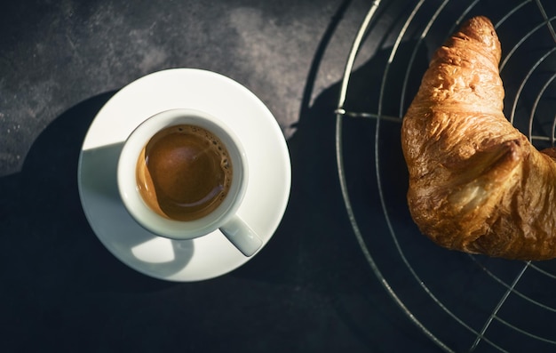 Hooghoekbeeld van een koffiekop met croissant op tafel