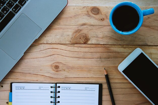 Foto hooghoekbeeld van een koffiekop met mobiel en laptop op tafel