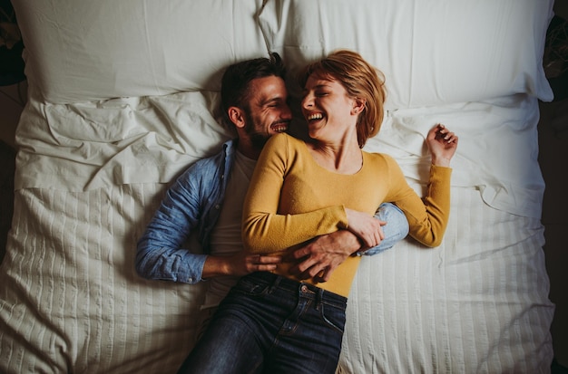 Hooghoekbeeld van een koppel dat elkaar omhelst terwijl ze thuis op bed liggen