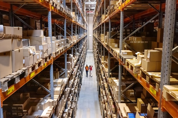 Hooghoekbeeld van een magazijnbeheerder die met voormanen de voorraad op de rekken controleert
