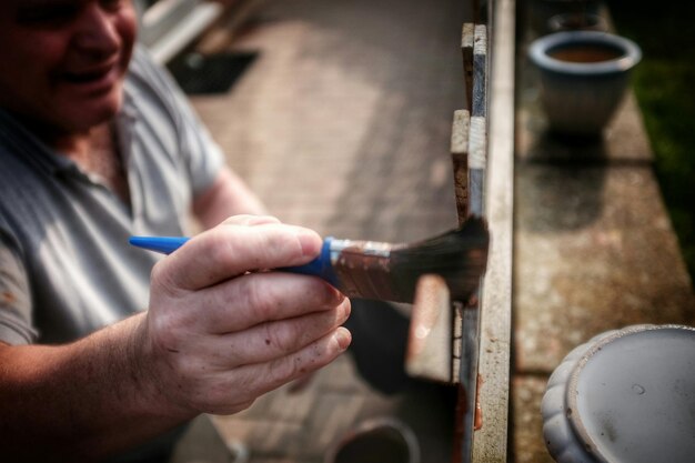 Foto hooghoekbeeld van een man die een houten hek schildert