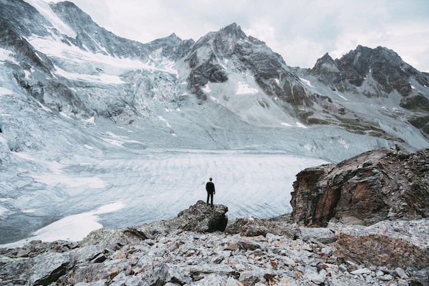 Hooghoekbeeld van een man die op een rotsformatie voor de Zwitserse Alpen staat