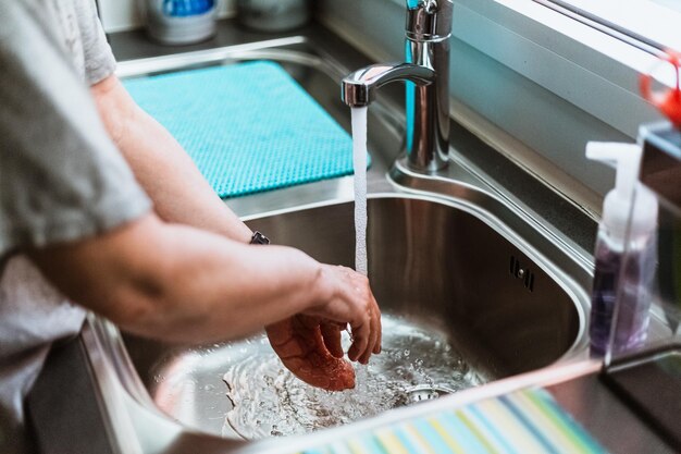 Hooghoekbeeld van een man die water uit de kraan drinkt