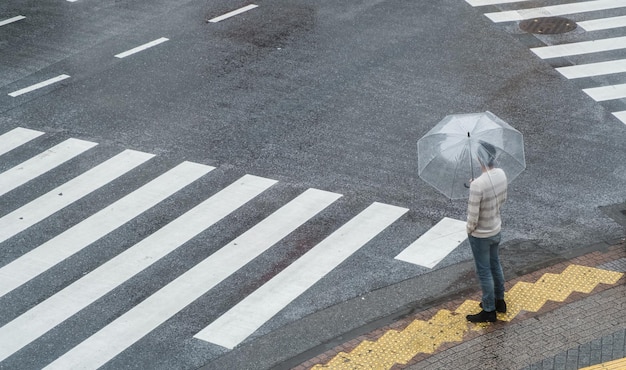 Hooghoekbeeld van een man met een paraplu terwijl hij tijdens het regenseizoen bij de weg staat