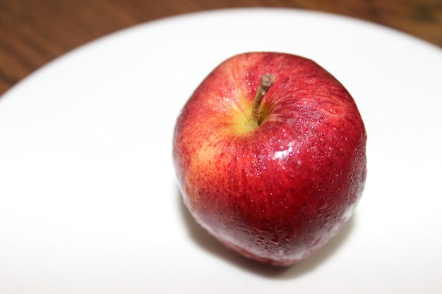Hooghoekbeeld van een natte rode appel in een witte plaat