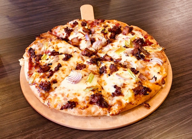 Hooghoekbeeld van een pizza die op een houten tafel wordt geserveerd