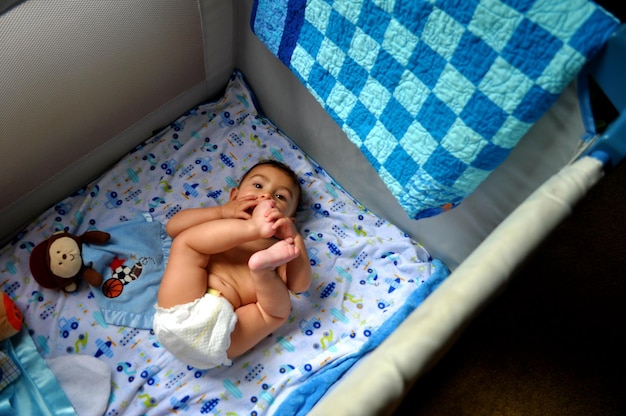 Hooghoekbeeld van een schattige baby die thuis in de wieg ligt