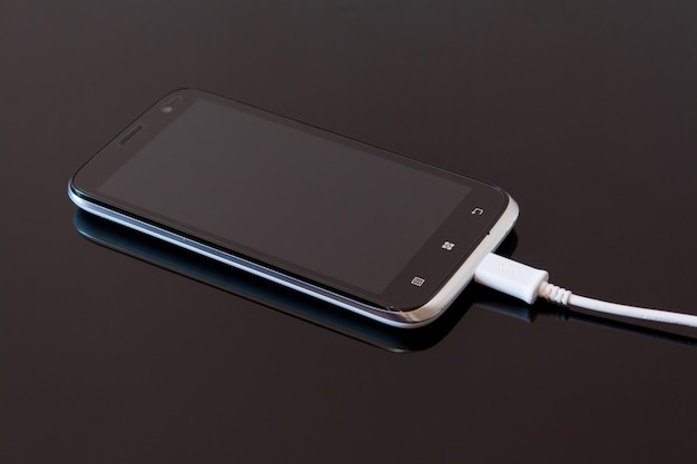 Hooghoekbeeld van een smartphone die is aangesloten op een oplader op een zwarte achtergrond