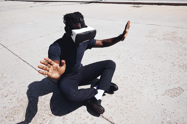 Hooghoekbeeld van een tiener die gebaren maakt tijdens het gebruik van virtuele realiteit op de weg tijdens een zonnige dag