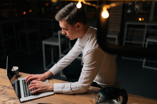 Hooghoekbeeld van een vermoeide jonge zakenman die laat in de nacht online overwerk doet in