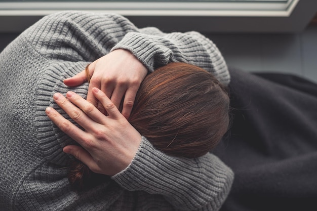 Foto hooghoekbeeld van een vrouw die thuis bij het raam zit