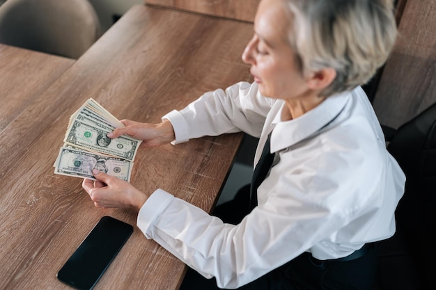 Foto hooghoekbeeld van een vrouw van middelbare leeftijd die contant geld telt en van financiële onafhankelijkheid geniet.