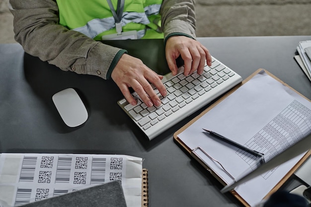 Hooghoekbeeld van een werknemer van een magazijn die online aan het werk is op een computer op haar werkplaats