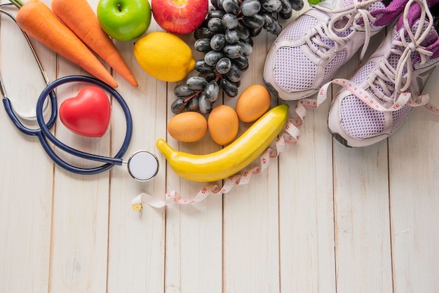 Hooghoekbeeld van fruit en schoenen met stethoscoop op een hardhouten vloer