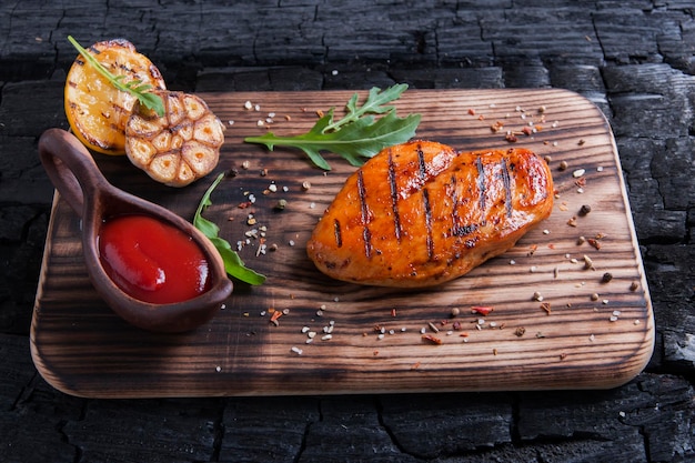 Hooghoekbeeld van gegrilde kip met saus geserveerd op de snijplank