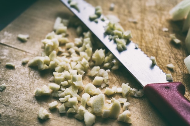 Foto hooghoekbeeld van gehakte knoflook en keukenmes op de snijplank