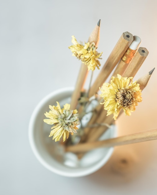 Foto hooghoekbeeld van gele bloemen met potloden in een container op tafel