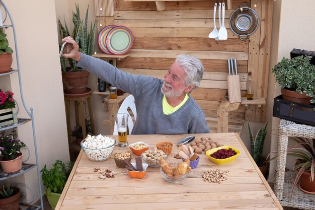 Foto hooghoekbeeld van glimlachende oudere man die een selfie maakt met eten op tafel thuis