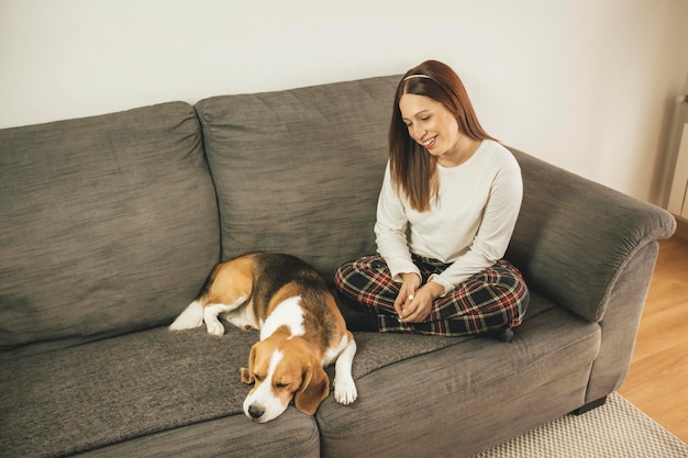 Hooghoekbeeld van glimlachende vrouw die thuis op de bank zit met een hond