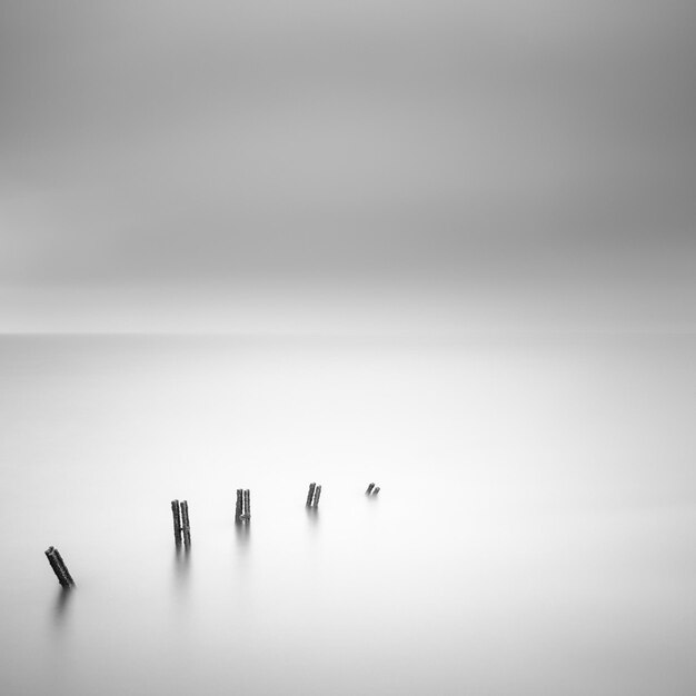 Hooghoekbeeld van houten palen in de zee tegen bewolkte lucht