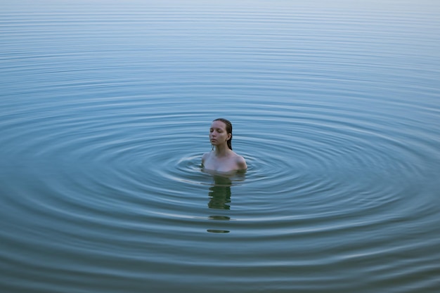 Hooghoekbeeld van jonge vrouw die in het meer zwemt