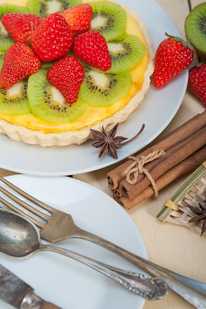Hooghoekbeeld van kiwi-taart op een bord met specerijen op tafel