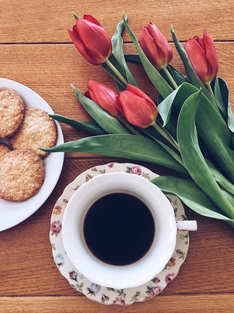 Hooghoekbeeld van koffie en koekjes met tulpen op tafel