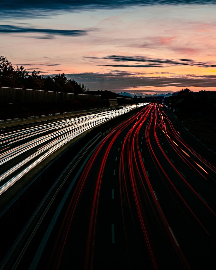 Foto hooghoekbeeld van lichtsporen op de weg's nachts met de alpen op de achtergrond