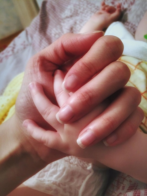 Hooghoekbeeld van moeder die baby's hand vasthoudt