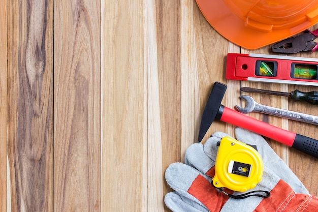 Hooghoekbeeld van oranje veiligheidshelm en gereedschappen op een houten tafelachtergrond