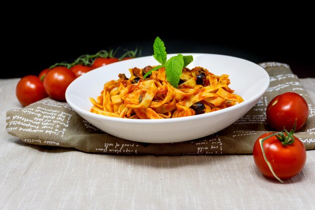 Foto hooghoekbeeld van pasta op een bord bij tomaten op tafel