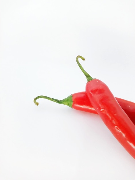Hooghoekbeeld van rode chili pepers tegen een witte achtergrond.