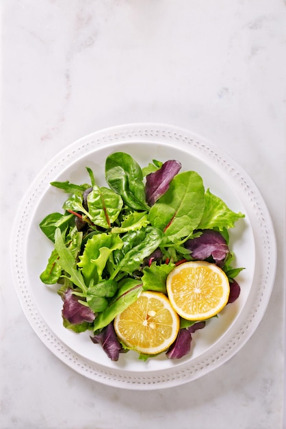 Hooghoekbeeld van salade en citroenen in een bord op tafel